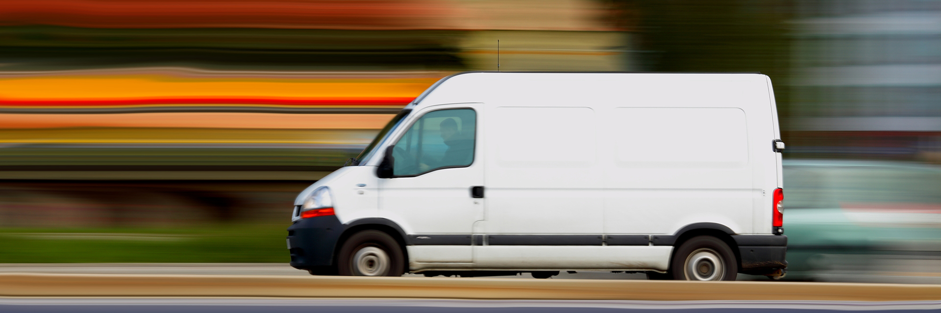 White van driving down the road with blurred background