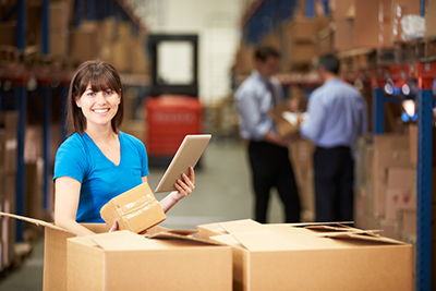 Woman holding clipboard in warehouse with boxes