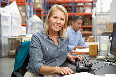 Blonde woman sitting a service desk in warehouse